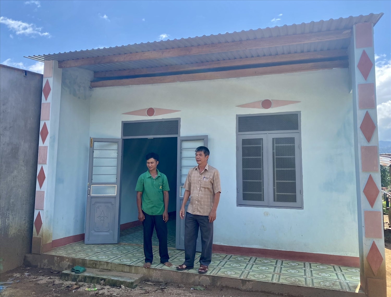Anh A Lễ (bên trái) ở thôn Tê Peng, xã Đăk Trăm, huyện Đăk Tô phấn khởi vì được hỗ trợ xây dựng căn nhà mới khang trang