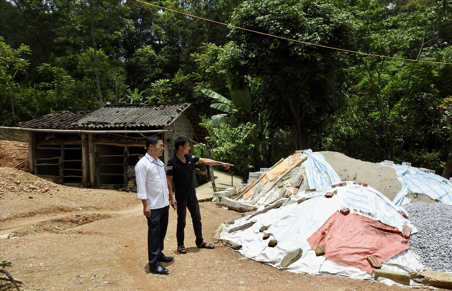 Bí thư Đảng uỷ xã Vân Thuỷ, huyện Chi Lăng - Hoàng Văn Phách (áo trắng) đi kiểm tra và động viên các gia đình được hỗ trợ xây dựng nhà ở 