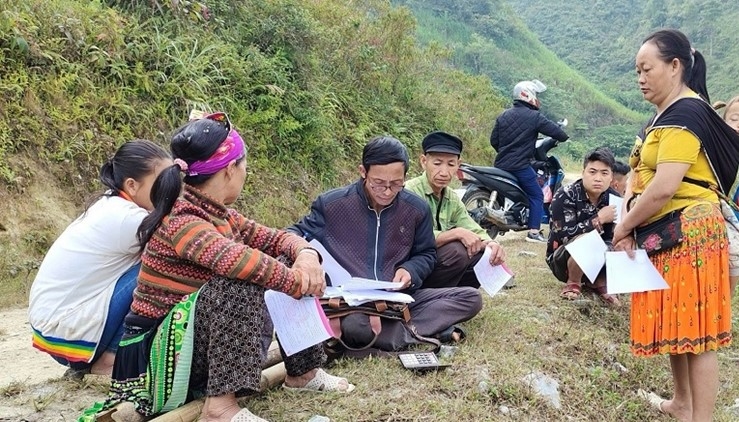 Ông Thào Minh Khyào, Người có uy tín thôn Nặm Khiếu, xã Nhạn Môn, huyện Pác Nặm (người mặc áo khoác đen) hướng dẫn người dân làm thủ tục vay vốn ngân hàng để phát triển sản xuất (Ảnh: Thanh Loan).