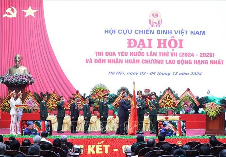 Tổng Bí thư Tô Lâm gắn Huân chương Lao động hạng Nhất lên lá cờ truyền thống Hội Cựu chiến binh Việt Nam - Ảnh: TTXVN