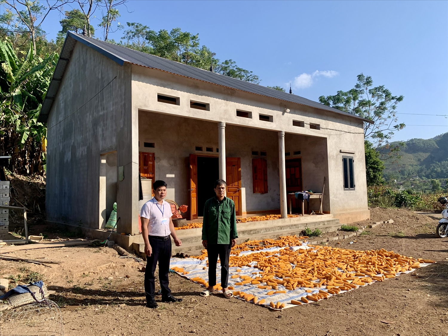 Ông Hoàng Văn Mạc (bên phải) bên ngôi nhà mới của gia đình