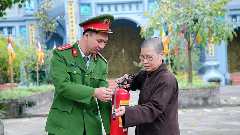 Cán bộ Công an xã Yên Mỹ, huyện Thanh Trì, Hà Nội hướng dẫn ni sư chùa Thanh Lan sử dụng bình cứu hỏa