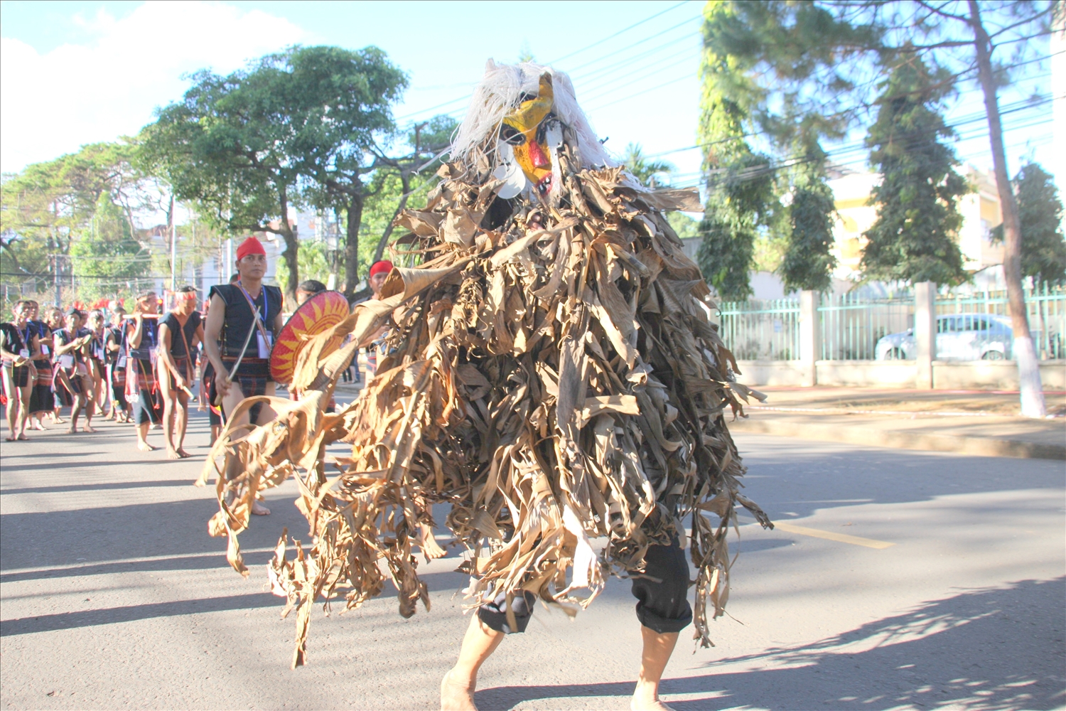 Pram đeo mặt nạ, tạo hình tóc bằng rễ cây, mặc bộ trang phục kết bằng lá chuối khô xuất hiện trong lễ hội đường phố