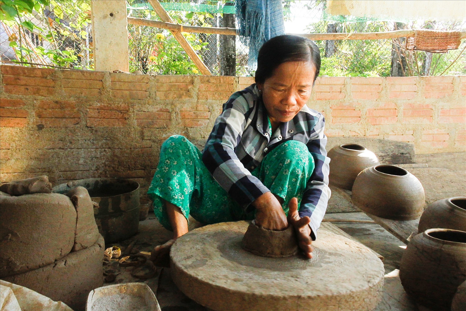 Người thợ gốm đang làm thủ công, tay tạo tác, chân đạp bàn xoay (Ảnh Nguyễn Trang)