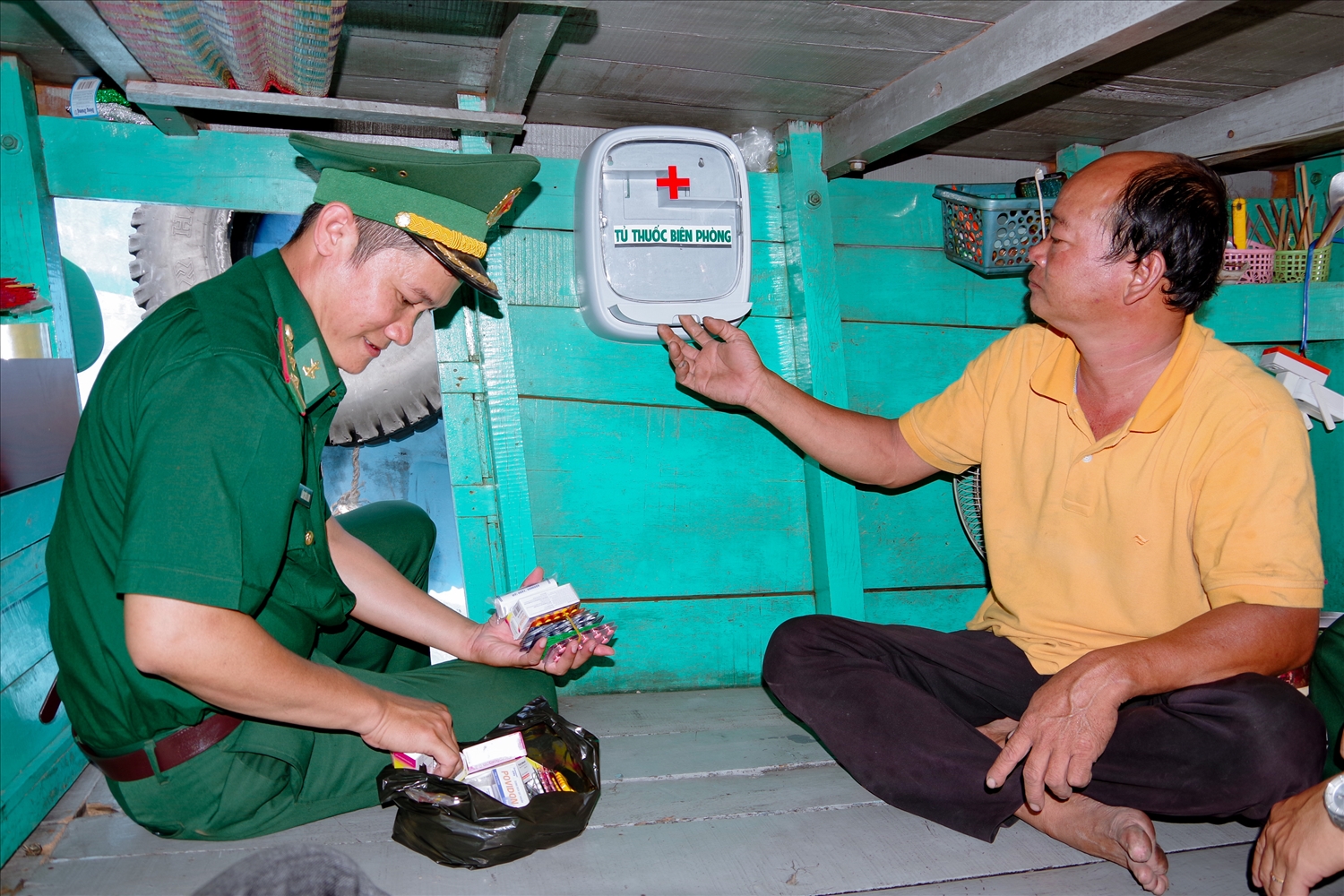 Cán bộ Hải đội 2 Biên phòng, Bộ đội Biên phòng Sóc Trăng lắp đặt tủ thuốc cho tàu cá ngư dân. Ảnh: Hoàng Đoán