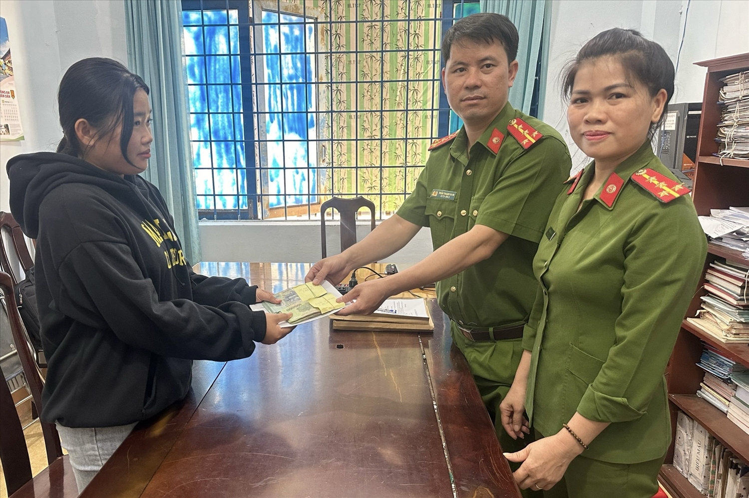 Cán bộ Công an huyện Cư Jút trao trả tiền bị đối tượng lừa đảo chiếm đoạt cho chị Hoàng Thị Diệu Mai