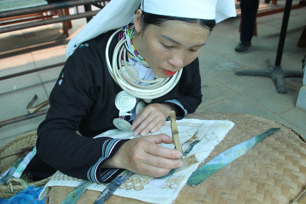 Đồng bào Dao Tiền tỉnh Cao Bằng giới thiệu nghề truyền thống in hoa văn sáp ong trên vải và thêu hoa văn lên khăn đội đầu