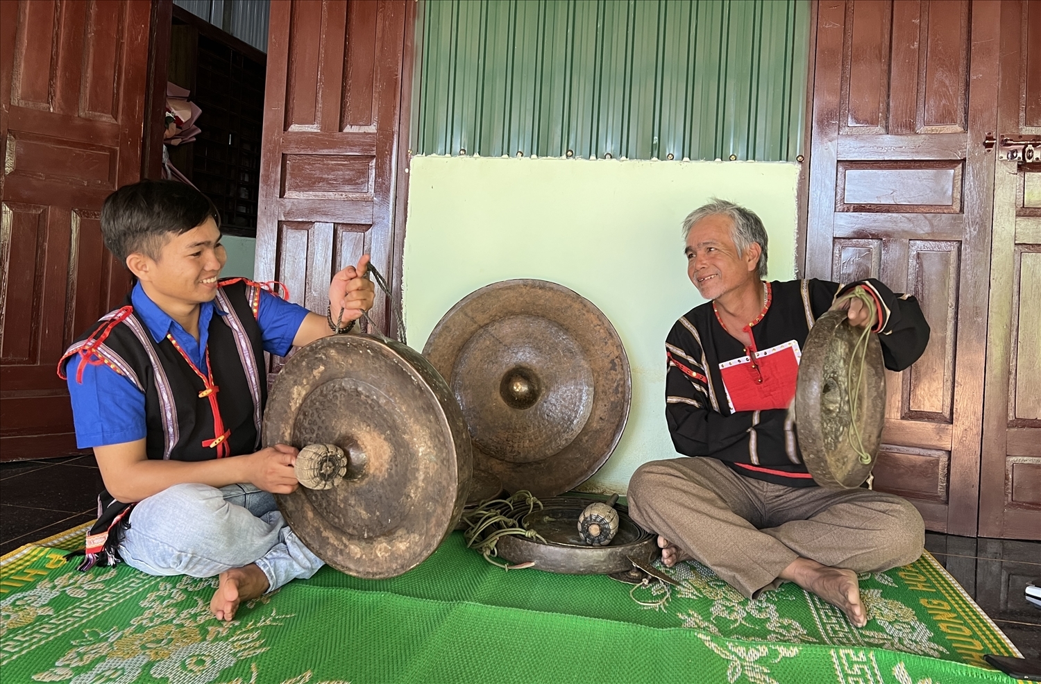 Siu Thanh cùng cha mình là nghệ nhân Nay Tek kiểm tra âm thanh bộ cồng chiêng của làng Plei Djriêk
