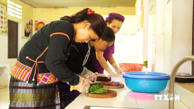 Các phụ huynh tham gia nấu ăn theo thực đơn riêng cho trẻ suy dinh dưỡng cùng với nhân viên nấu ăn ở Trường Mầm non Hướng Phùng. Ảnh: Thanh Thuỷ-TTXVN