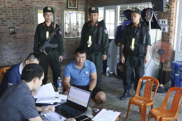 Lực lượng công an thi hành lệnh khám xét khẩn cấp đối với Nguyễn Xuân Hùng (áo xanh, ngồi chính giữa) ở xã Vạn Trạch (H.Bố Trạch, Quảng Bình) liên quan đến đường dây cá độ bóng đá