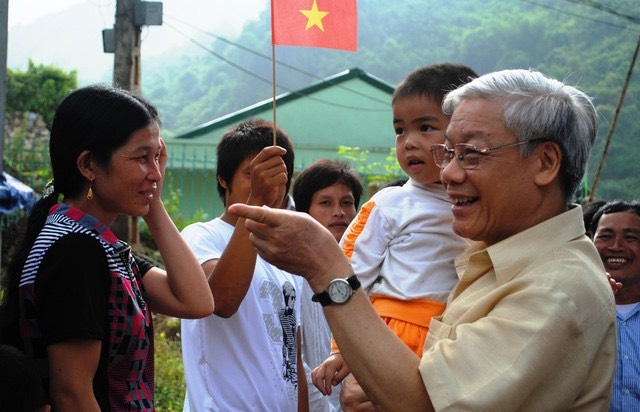 Tổng Bí thư Nguyễn Phú Trọng bế một cháu nhỏ khi thăm, nói chuyện với bà con nhân dân bản Sáng, xã Quang Chiểu, huyện Mường Lát.