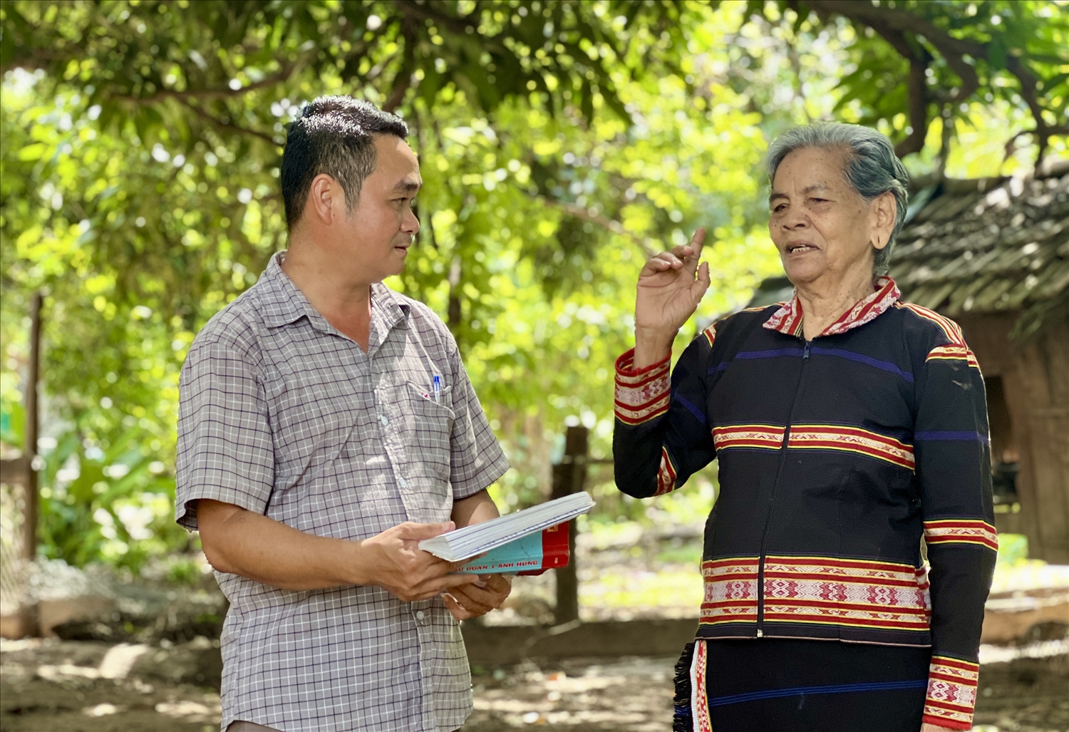 Phó Chủ tịch UBND xã Ia Mơ, huyện Chư Prông Nguyễn Tuấn Anh (bên trái) cùng già làng trao đổi về công tác tuyên truyền, vận động người dân thay đổi nếp nghĩ, cách làm