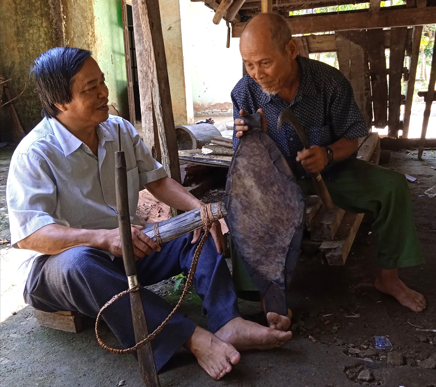 Già An (bên phải) đang kể cho tác giả nghe về khiên trong đời sống đồng bào Ca Dong.