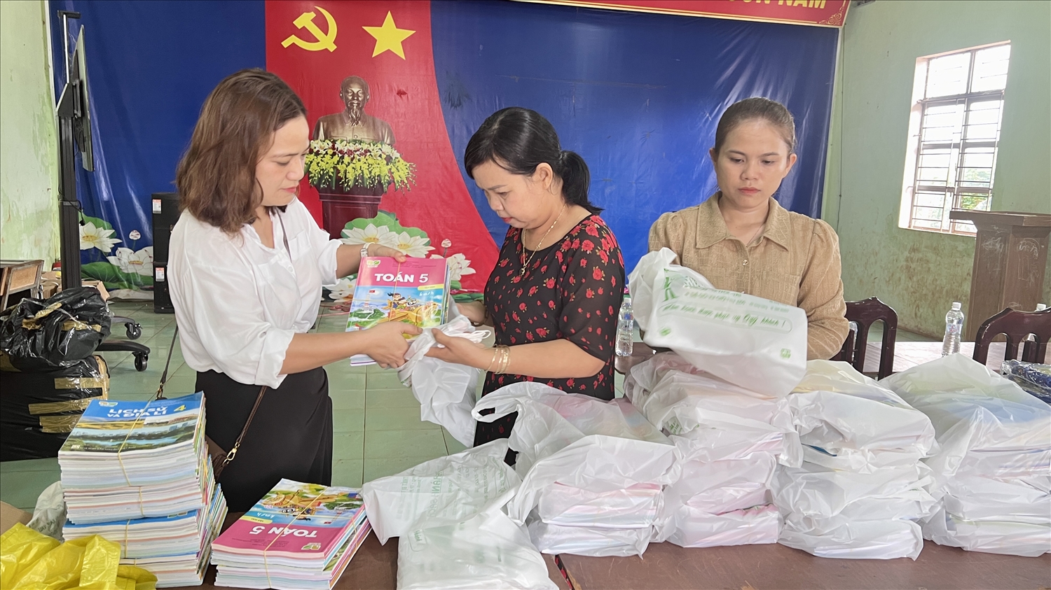 Đại diện thường trú Báo Dân tộc và Phát triển tại Gia Lai cùng Ban giám hiệu nhà trường chuẩn bị sách giáo khoa cho học sinh