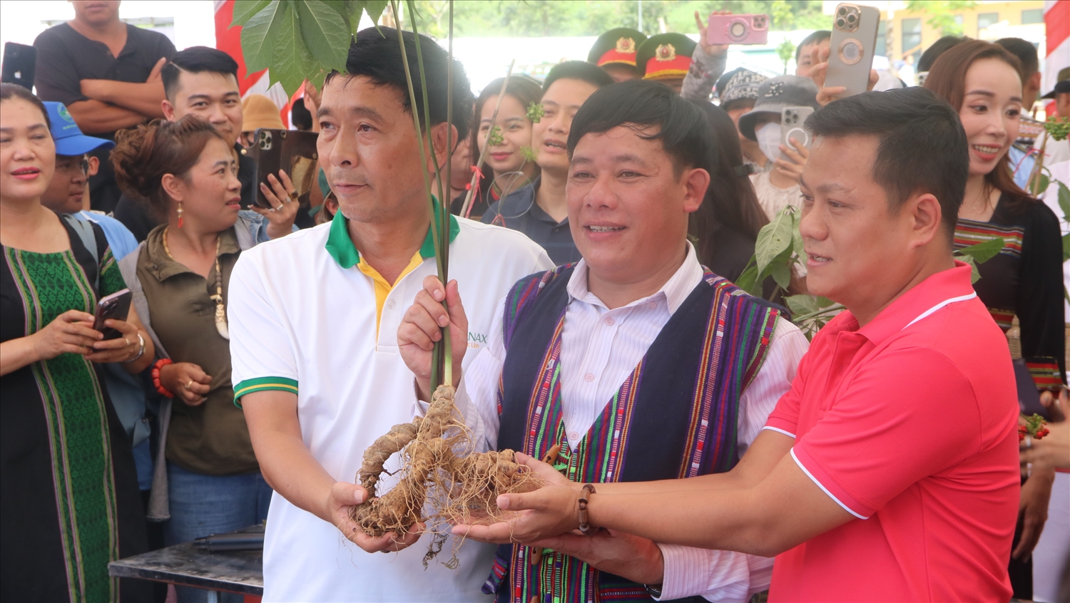 Ông Nguyễn Văn Lượng (giữa) tặng cây sâm Ngọc Linh nặng 2,6 lạng được giải đặc biệt và 2 cây sâm khác để đấu giá ủng hộ Quỹ xóa nhà tạm.