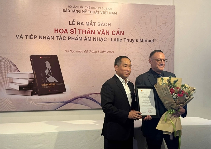 Giám đốc Bảo tàng Mỹ thuật Việt Nam Nguyễn Anh Minh tặng hoa và thư cảm ơn nhạc sỹ Paul Zetter (bên phải)- tác giả tác phẩm âm nhạc “Little Thuy's Minuet