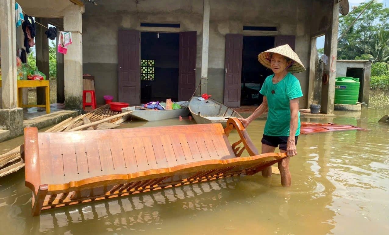 Bà Nguyễn Thị Hợp (71 tuổi, ở khu phố Ngọc Bồ) buồn rầu nhìn vật dụng trong nhà bị ngập lụt sau lũ 