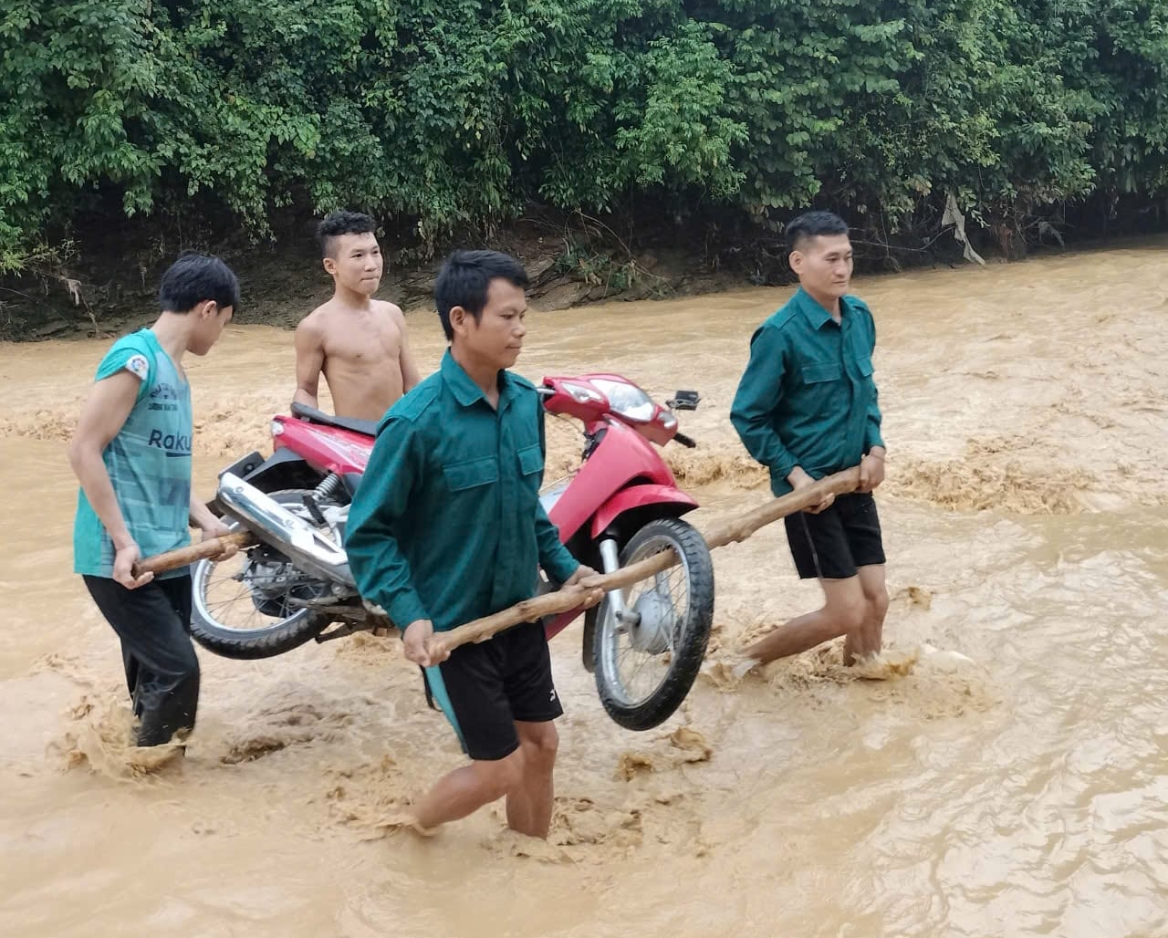 Mưa lớn khiến nước khe suối dâng cao làm ngập các cầu tràn, lực lượng dân quân xã phải hỗ trợ người và phương tiện lưu thông.