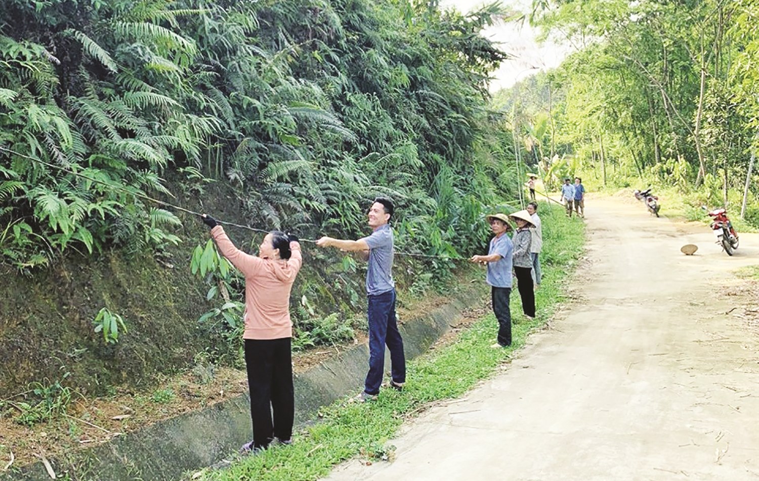 Bà La Thị Duyên (áo cam) tham gia kéo đường điện thắp sáng đường quê trong thôn Làng Đát