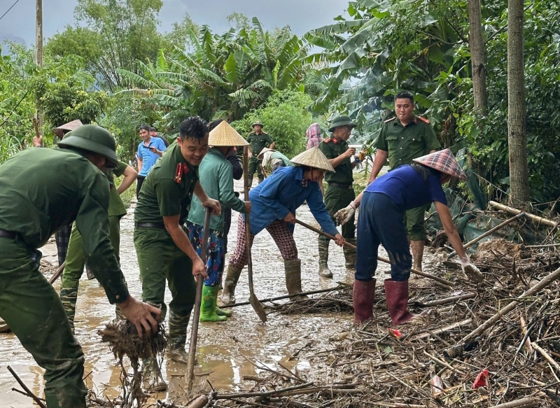 Công an xã Điền Lư cùng người dân dọn đường sau khi nước lụt rút.