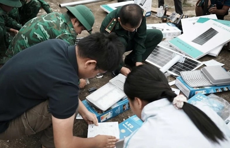 Các thành viên trẻ cùng cán bộ, chiến sĩ biên phòng Bát Mọt lắp đặt đèn năng lượng mặt trời phục vụ sinh hoạt của người dân. Ảnh: CTV 