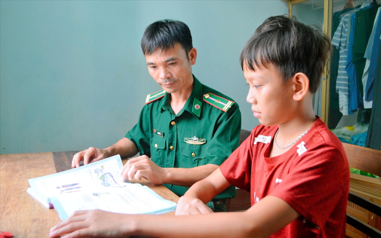 Cán bộ Đồn Biên phòng SêRêPốk hướng dẫn ""con nuôi" học bài- Ảnh: Lê Hường