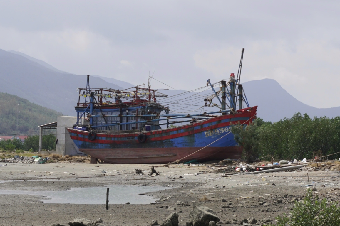 Một con tàu bị gió bão và sóng đánh dạt lên bờ. (Ảnh: T.L)