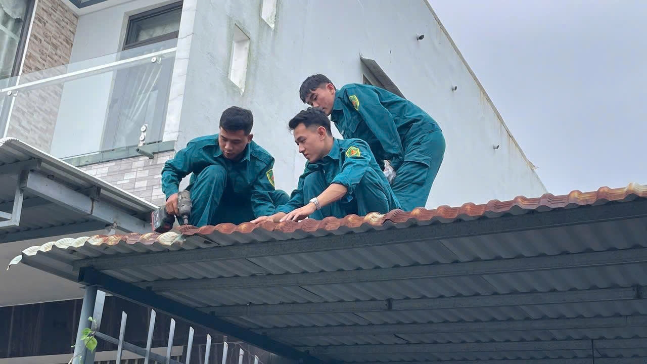 Lực lượng chức năng hỗ trợ người dân lợp lại nhà sau lốc xoáy. (Ảnh Huy Trường)