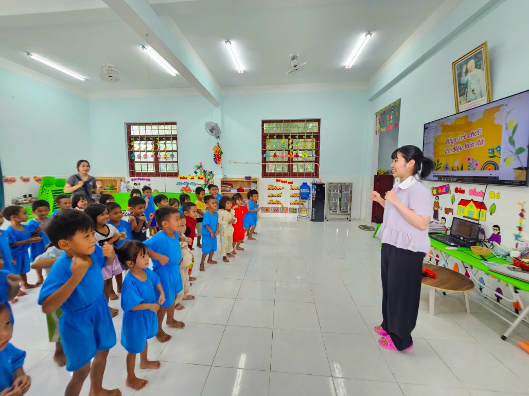 Các em học sinh mẫu giáo làng Canh Tiến say mê múa theo điệu nhạc phát từ chiếc tivi. (Ảnh: T.N)