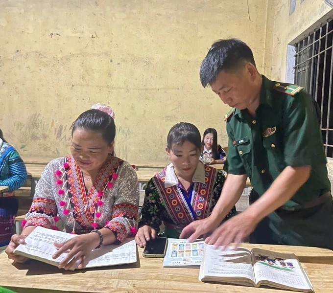 Thiếu tá Hơ Văn Di hướng dẫn học viên học chữ trong lớp học buổi tối tại bản Cánh Cộng, xã Trung Lý, huyện Mường Lát cũ.