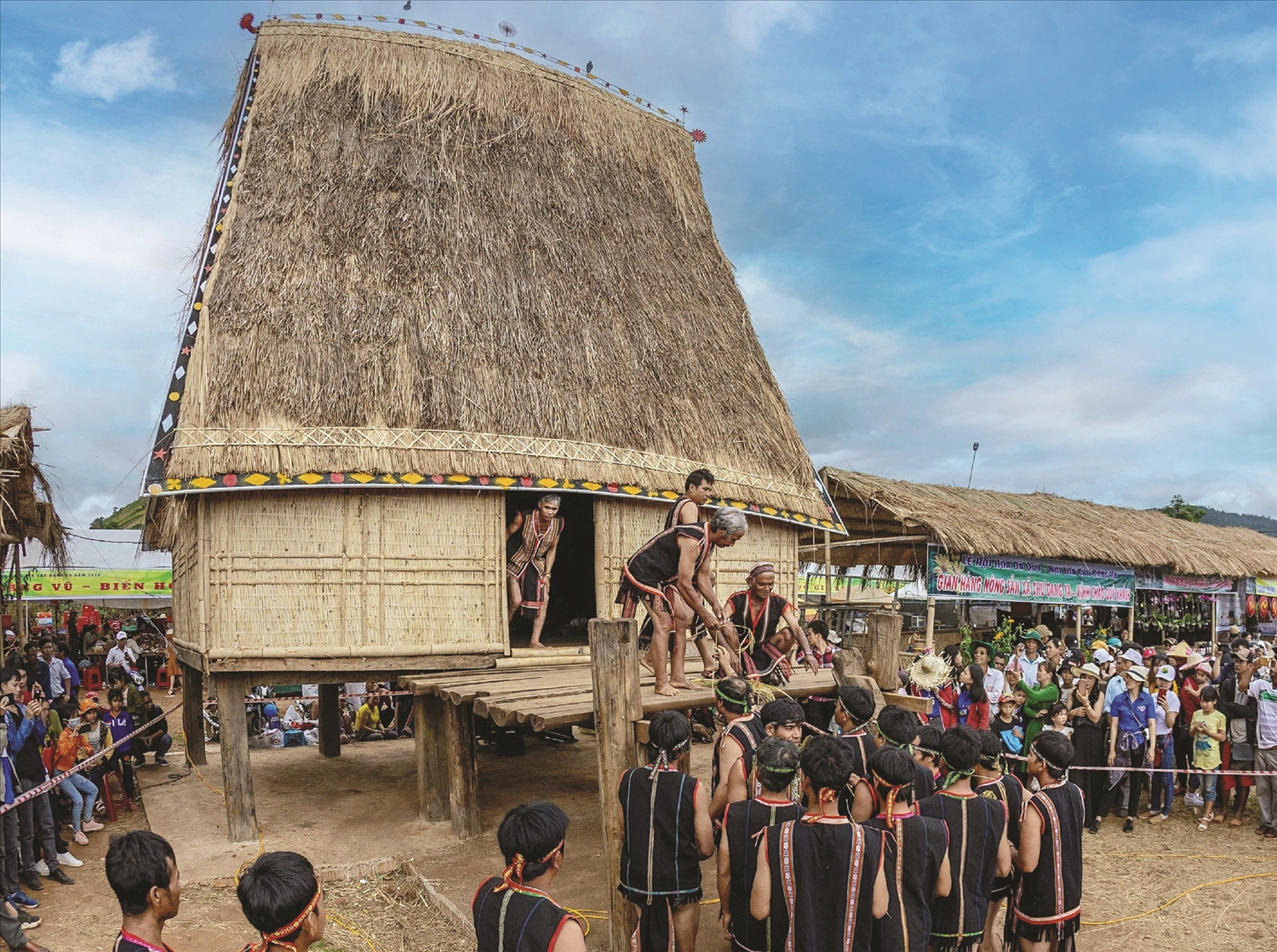 Dân làng tề tựu trước nhà rông, ai ai cũng nở nụ cười rạng rỡ, trên tay mỗi người đều cầm theo nhành lúa đẹp nhất từ chính ruộng, rẫy nhà mình