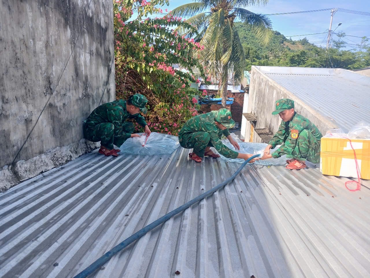 Lực lượng chức năng chằn chống nhà cửa giúp dân. (Ảnh Quý Quý)