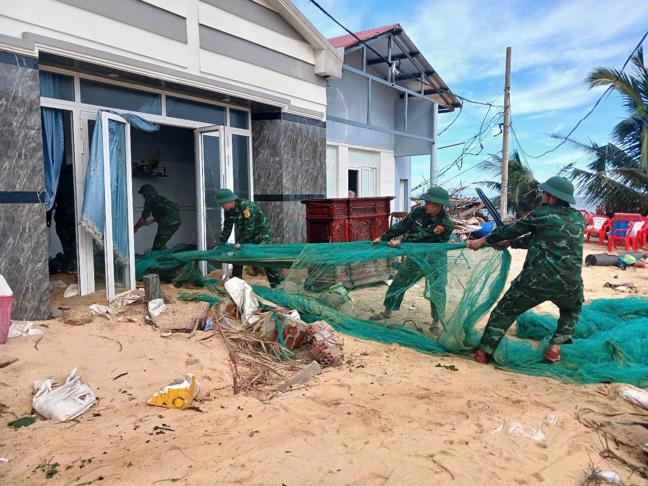 Cán bộ, chiến sĩ Đồn Biên phòng Cát Khánh, xã Đề Gi giúp dân dọn dẹp nhà cửa sau cơn bão số 13