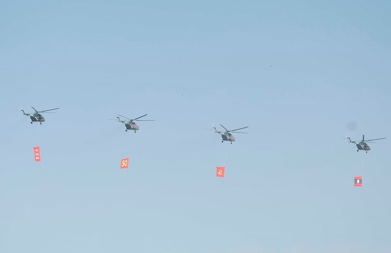 Biên đội máy bay trực thăng mang cờ bay trên bầu trời khu vực tổ chức lễ kỷ niệm. (Ảnh: Thống Nhất/TTXVN)