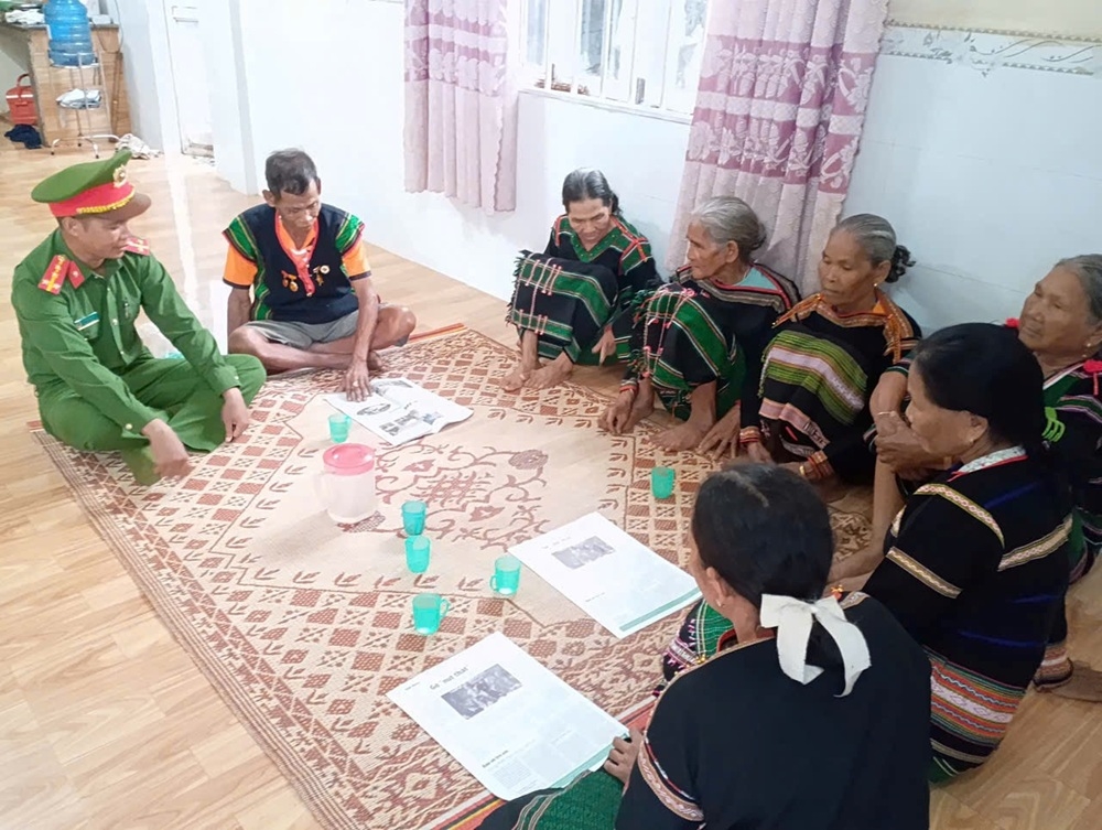 Già làng Y Xuyên (người ngồi cạnh cán bộ Công an xã Nâm Nung) tuyên truyền, vận động bà con bon Ja Ráh chấp hành chủ trương, pháp luật