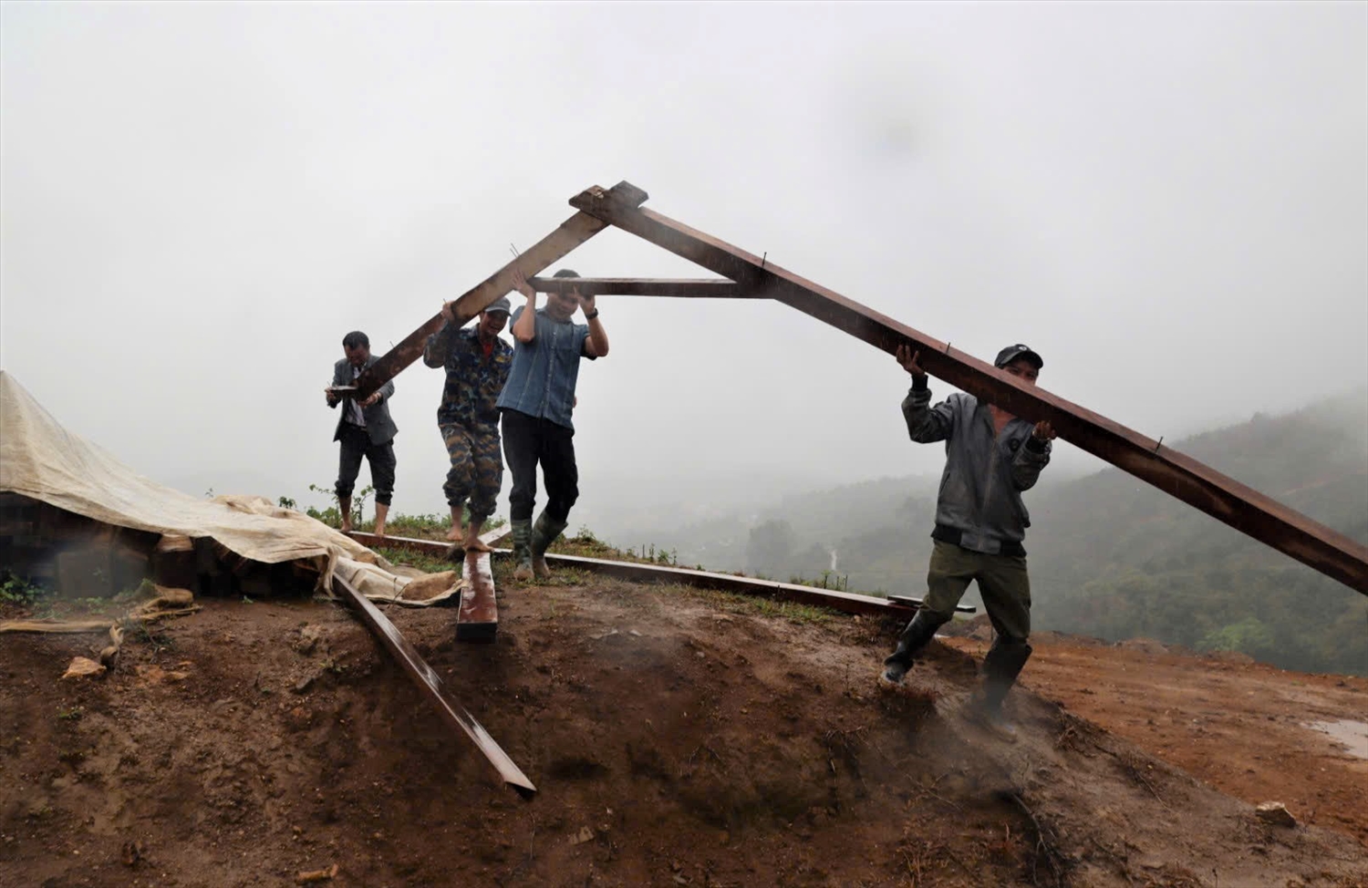 Cán bộ xã Măng Ri hỗ trợ người dân tháo dỡ nhà ở vùng sạt lở chuyển đến khu vực tái định cư. (Ảnh: Ngọc Chí)