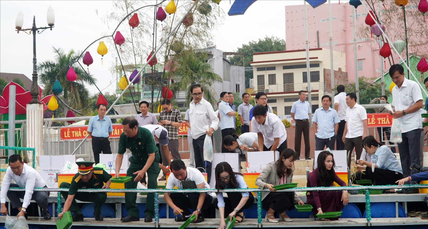 Các đại biểu tiến hành thả con giống tái tạo nguồn lợi thủy sản trên đầm Đông Hồ