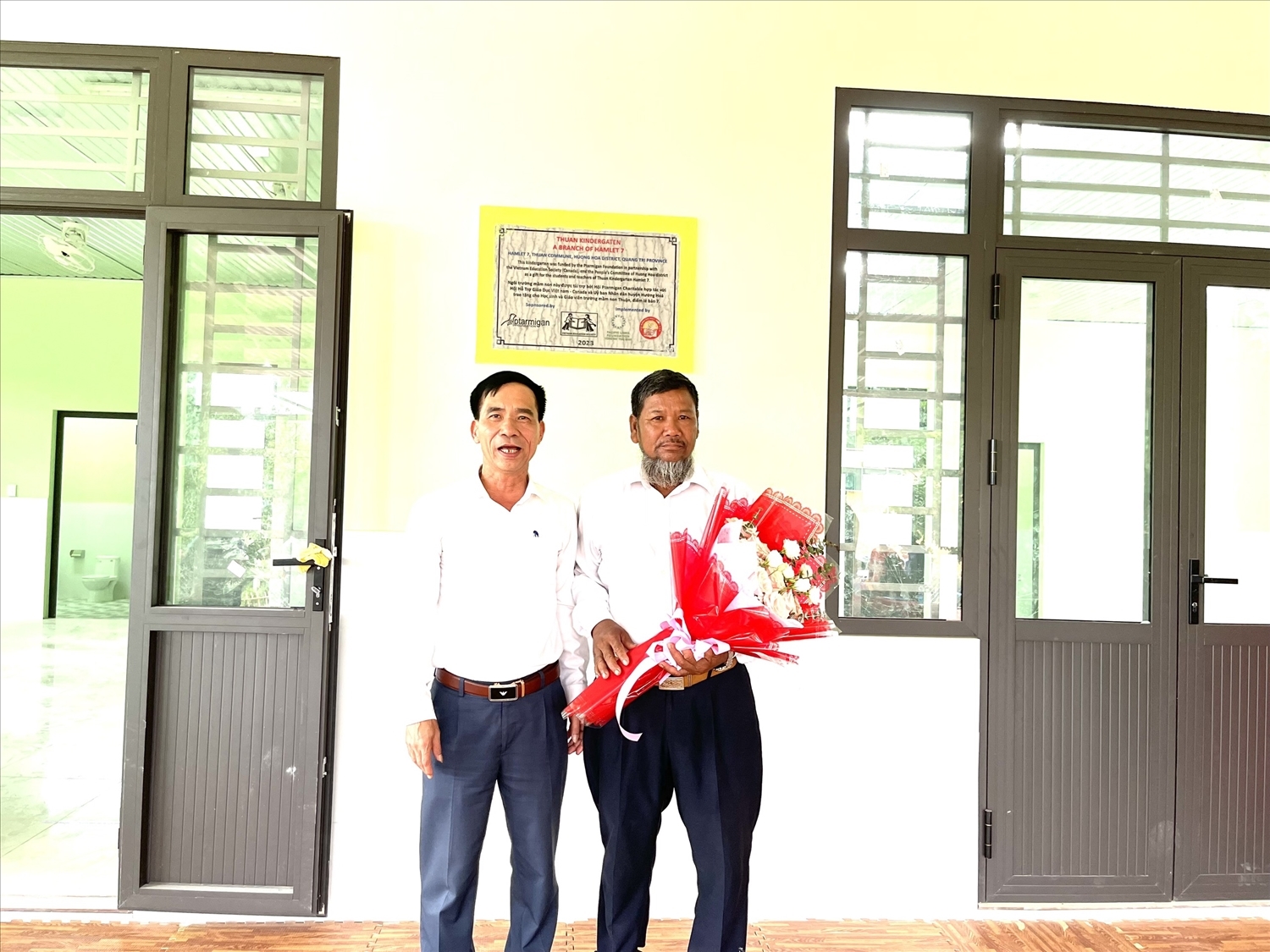 Ông Phạm Trọng Hổ (bên trái), Phó chủ tịch UBND huyện Hướng Hóa (Quảng Trị) tặng hoa biểu dương ông Hồ Văn Hạnh vì đã tự nguyện hiến đất mở rộng trường học