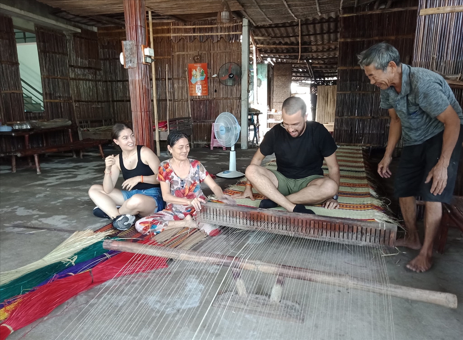 Du khách nước ngoài thích thú trải nghiệm nghề dệt chiếu ở Trà Nhiêu.