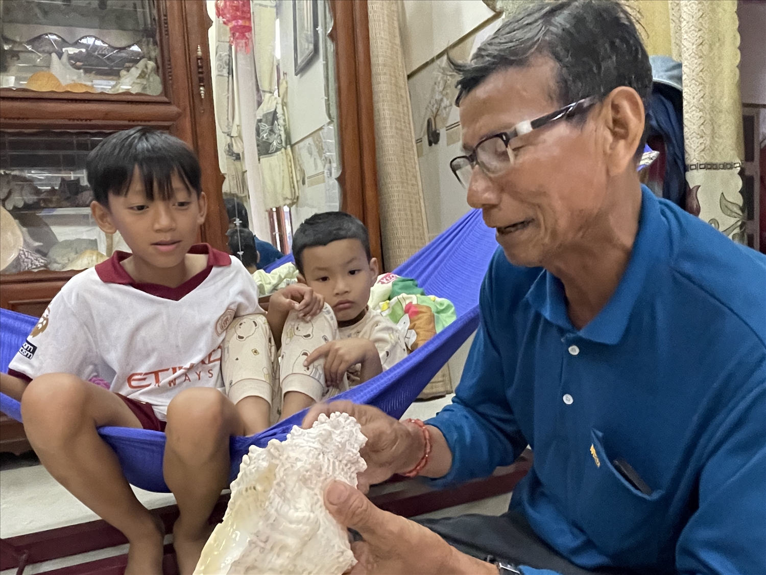 Ông Lê Hổ dạy cháu cách thổi ốc u.