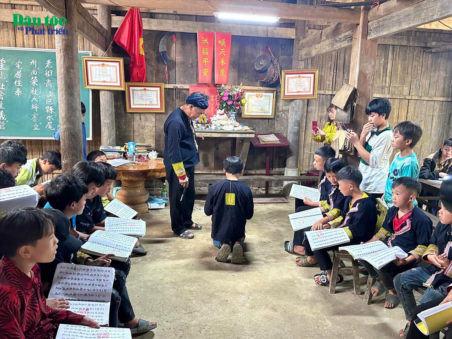 Nghệ nhân Ưu tú Tẩn Vần Siệu đang hướng dẫn các em nhỏ học chữ Nôm Dao, thực hành những nghi thức cúng bái đầu tiên trong đời