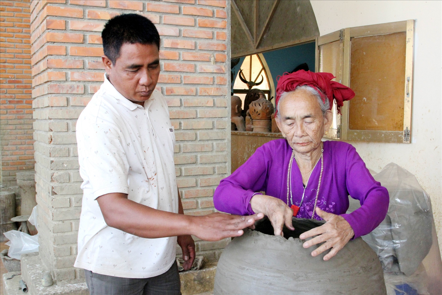 Ông Phú Hữu Minh Thuần, Giám đốc HTX Gốm Chăm Bàu Trúc trao đổi kỹ thuật chế tác bình gốm theo yêu cầu của khách hàng. 