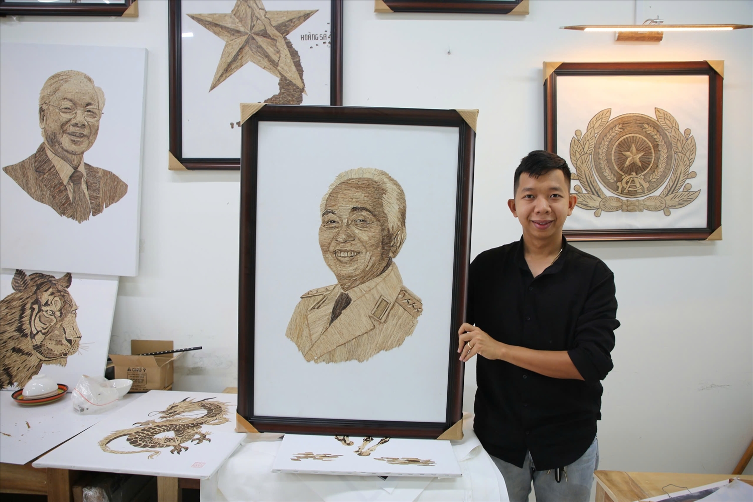 Anh Lê Ngọc Đức bên các bức tranh được xé dán từ trầm hương.