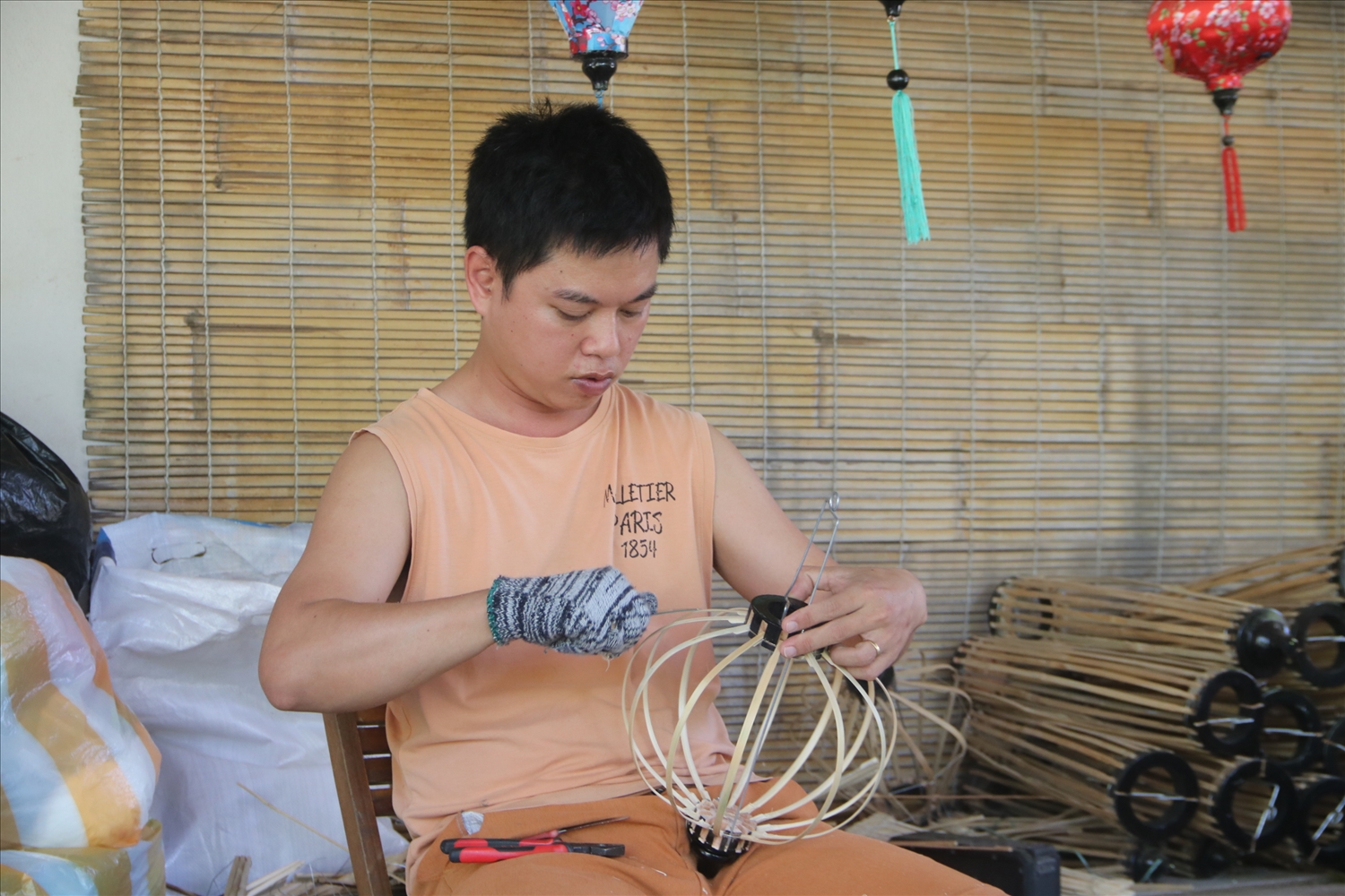 Anh Nguyễn Tấn Ngọc trước kia làm ăn xa, nay đã về học và làm đèn lồng đèn tại xưởng của gia đình anh Hà (Trong ảnh: Anh Nguyễn Tấn Ngọc thực hiện công đoạn tạo sườn cho lồng đèn