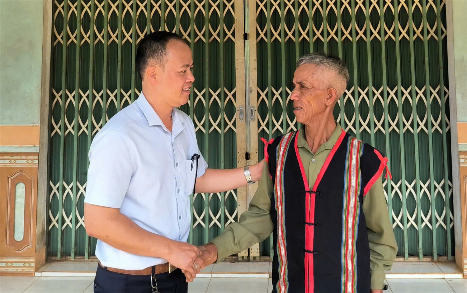 Chủ tịch UBND xã Đăk Na thăm hỏi ông A Dum (bên phải), già làng, Người có uy tín làng Lê Văng, xã Đăk Na, huyện Tu Mơ Rông 