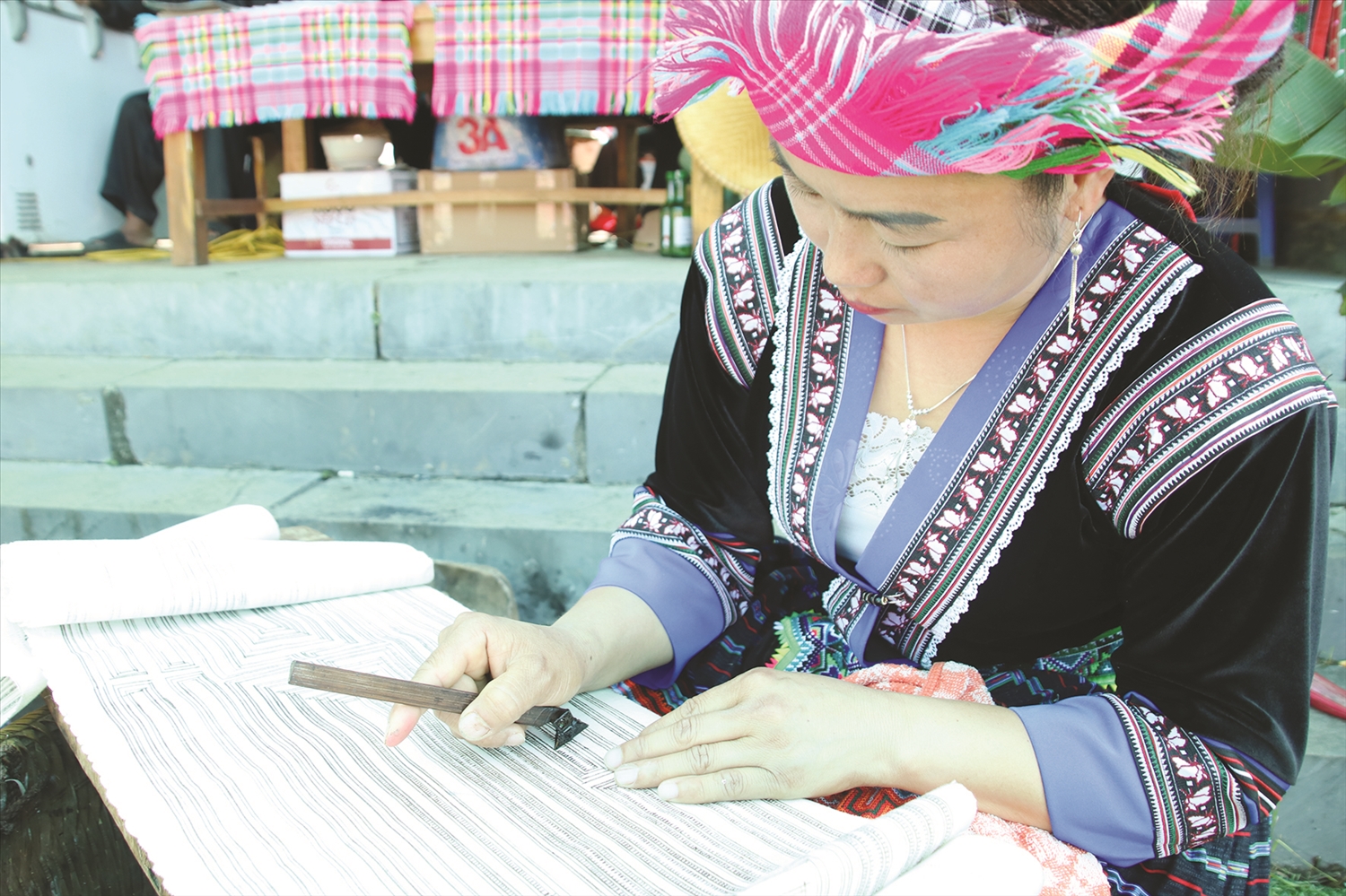 Khi vẽ hoa văn trên vải lanh, người phụ nữ Mông đặt vải lên một tấm ván bằng phẳng và nhẵn
