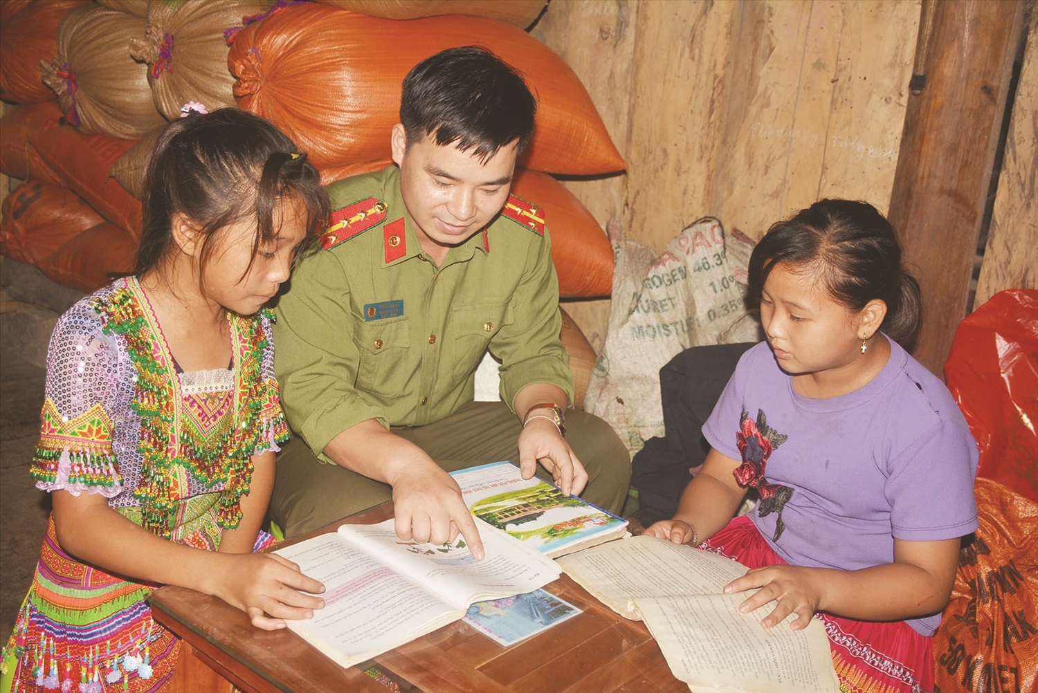 Một cán bộ công an hướng dẫn các cháu học sinh dân tộc Mông học bài. (Ảnh chụp tại thôn Đông Đăm, (xã Thượng Nông, huyện Na Hang, tỉnh Tuyên Quang).
