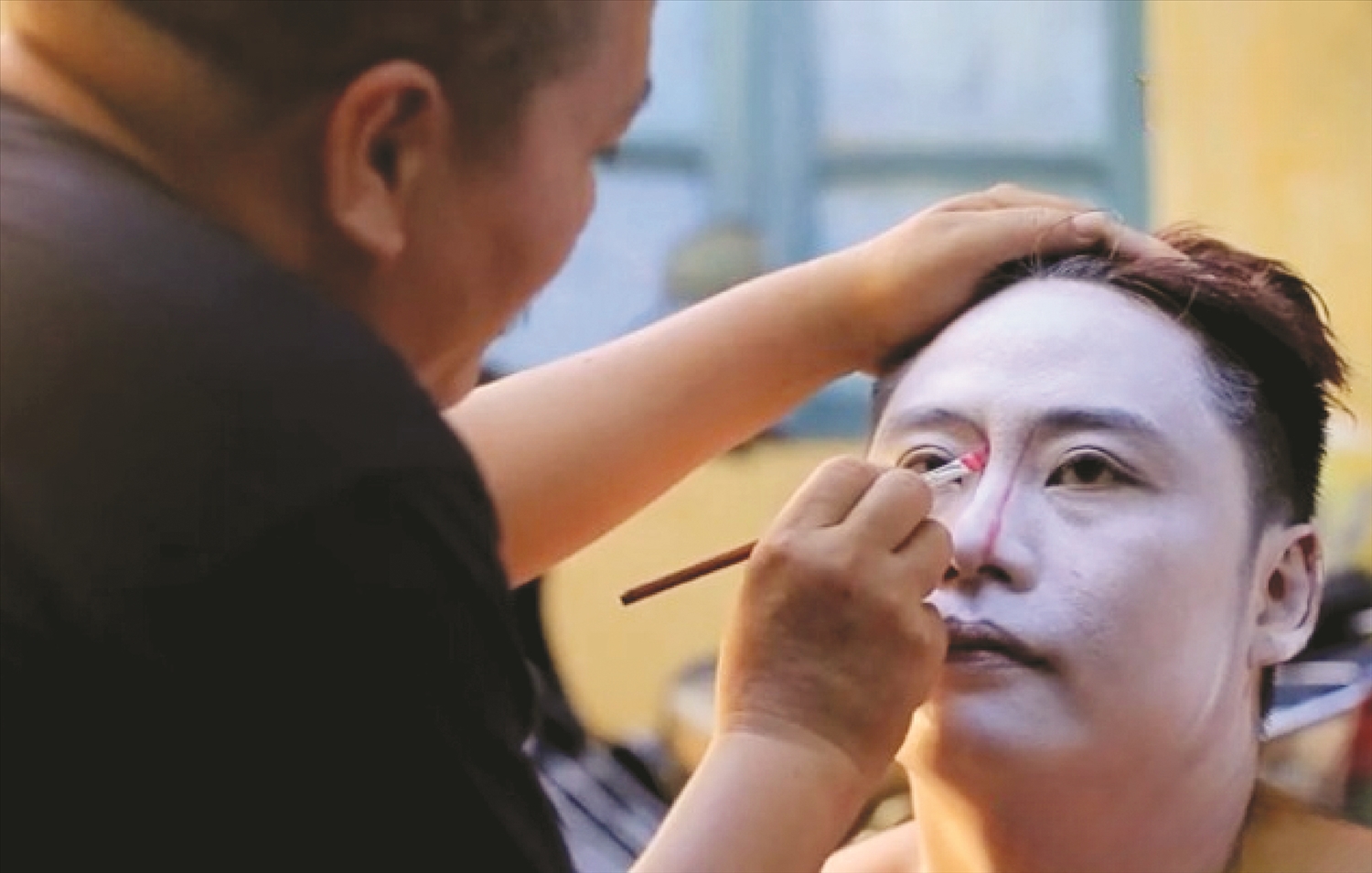 Đằng sau ánh đèn sân khấu là người đàn ông tỉ mỉ chừng chút một có từng diễn viên chuẩn bị bước lên sân khấu.