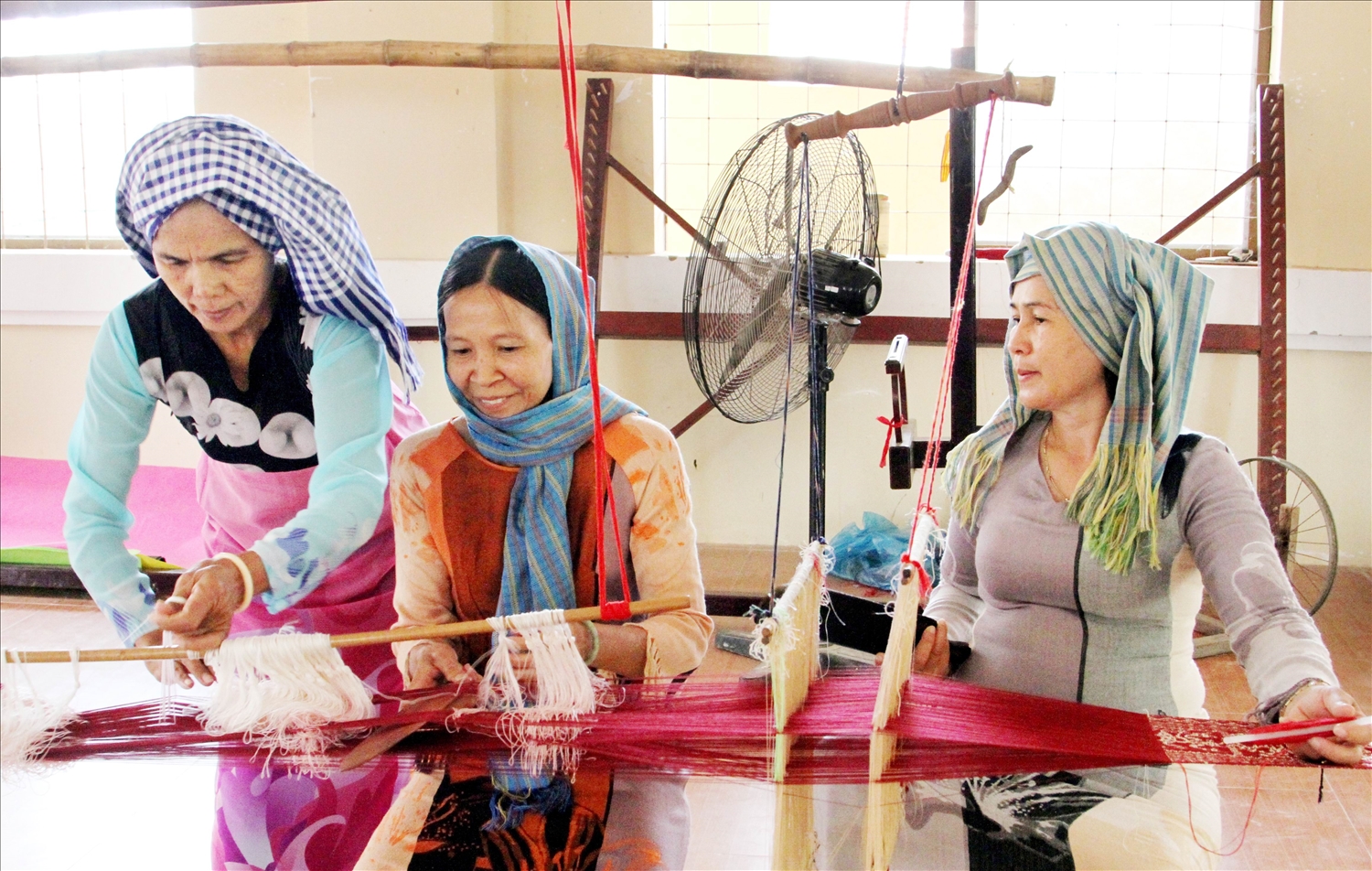 Nghệ nhân Đạt Thị Nam (bìa trái) tận tâm truyền nghề dệt hoa văn cổ cho phụ nữ làng Chăm Mỹ Nghiệp.