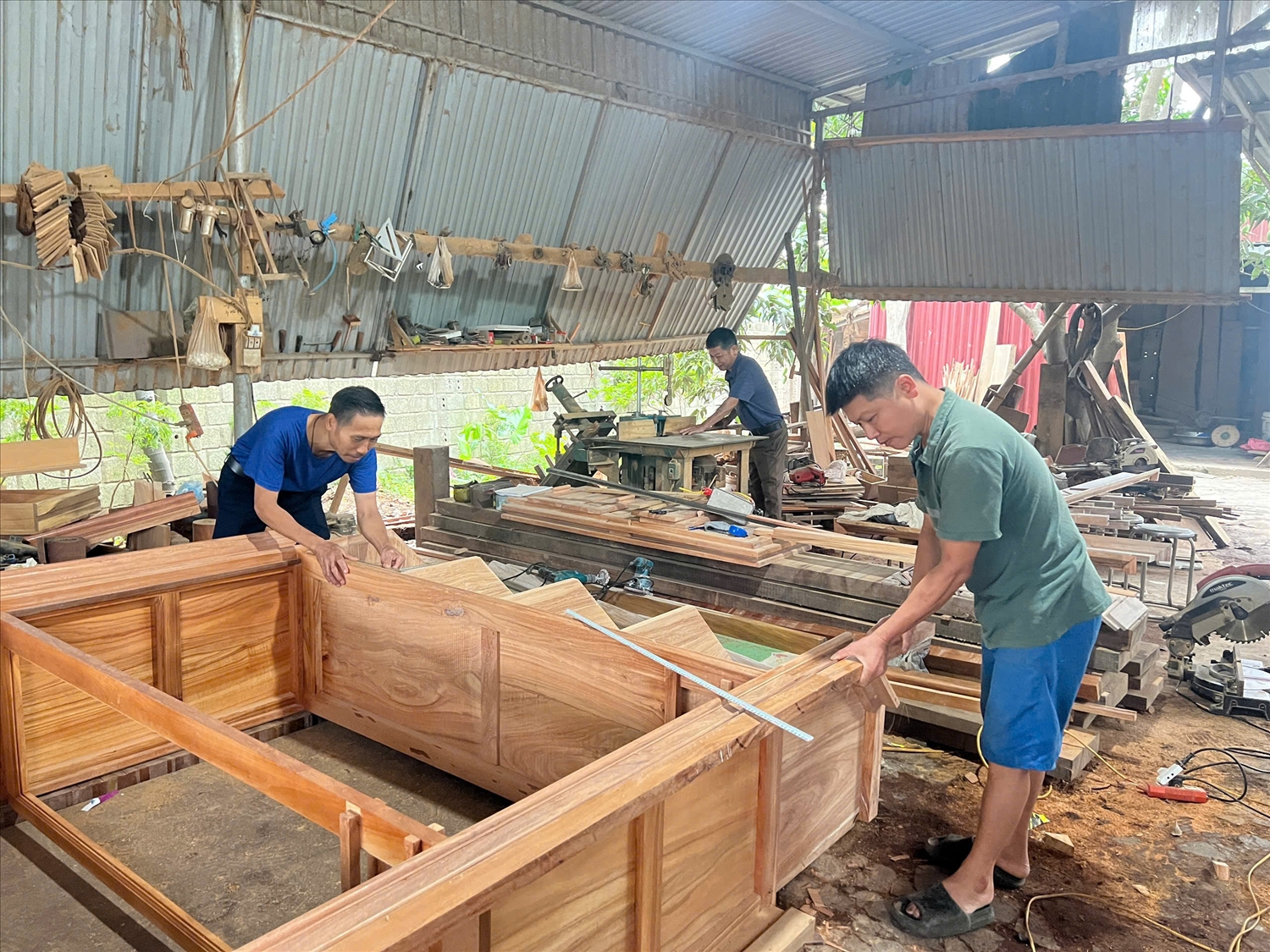 Anh Vũ Văn Hưng cùng các công nhân đang thực hiện các công đoạn hoàn thành tủ gỗ